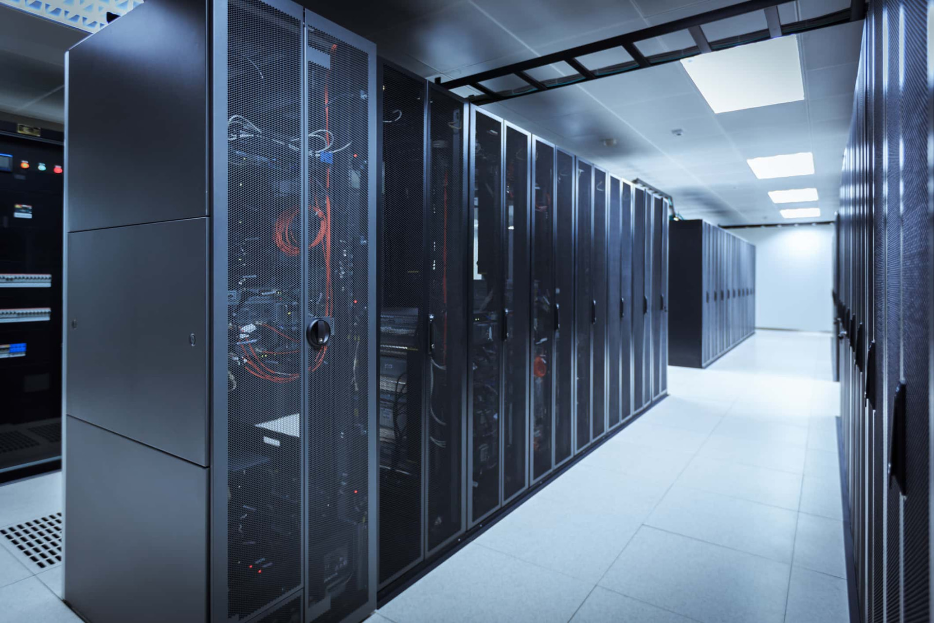 Data centre aisle lined with Cannon server cabinets, with overhead cable trays and a raised access floor